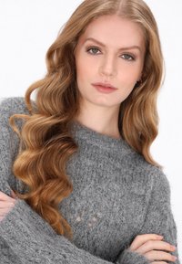 Szary sweter dziany o miękkim, teksturowanym wykończeniu, z luźnym krojem, szerokimi rękawami i małymi otworami w tkaninie zapewniającymi oddychalność.