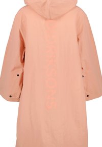 Světle růžová bunda s kapucí a širokými rukávy, černé patentky u manžet a vertikální text "DIDRIKSONS" tištěný na zadní straně.
