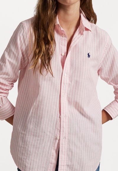 Camicia a maniche lunghe di un rosa chiaro con bottoni, caratterizzata da sottili righe verticali bianche e un piccolo logo blu navy. Realizzata in un tessuto testurizzato con un taglio classico.