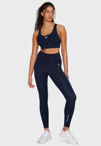 Set di reggiseno sportivo blu navy e leggings a vita alta realizzati in materiale elastico. Include un piccolo logo sul reggiseno e sui leggings.