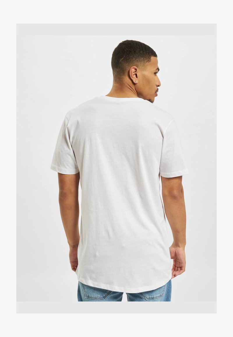 Man with short hair wearing a plain white short-sleeve T-shirt and blue jeans, shown from the back against a plain background.