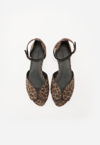 Leopard print sandals with an open toe design, brown and black fabric, ankle strap with buckle, and black textured interior.