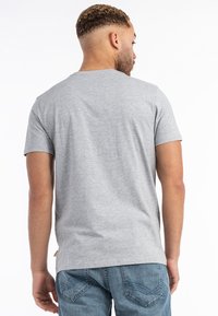 Grå kortærmet t-shirt lavet af bomuld med en klassisk rund halsudskæring, glat tekstur og en afslappet pasform, parret med blå denim jeans.