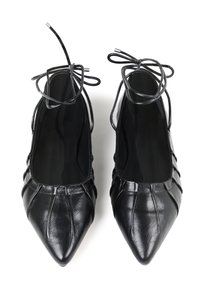 Bailarinas de cuero negro con punta afilada, que presentan un diseño plisado y cordones finos. Interior mate con textura suave y adornos mínimos.