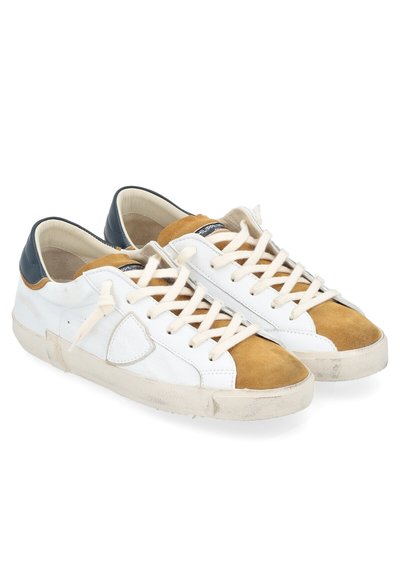 Baskets en cuir blanc avec des accents en daim beige, lacets crème et détail de talon bleu marine. Semelles en caoutchouc abîmées et dessus texturé.