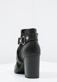Czarne botki za kostkę wykonane z syntetycznej skóry, z paskiem i srebrnymi detalami, o masywnym obcasie i gładkiej teksturze.