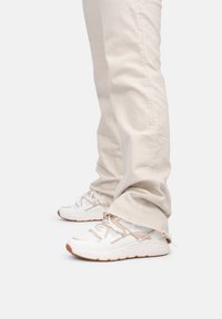 Witte sportieve schoenen van mesh en synthetisch materiaal, met beige accenten en een gestructureerde rubberen zool. Draag je met lichtbeige broek.