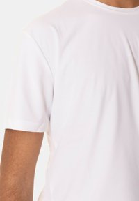 T-shirt bianco a maniche corte realizzato in tessuto liscio; presenta un collo a giro e una trama sottile con una vestibilità rilassata. Nessun motivo o dettaglio visibile.