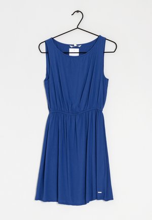 Robe bleue sans manches avec taille froncée suspendue sur un cintre noir sur fond blanc uni.