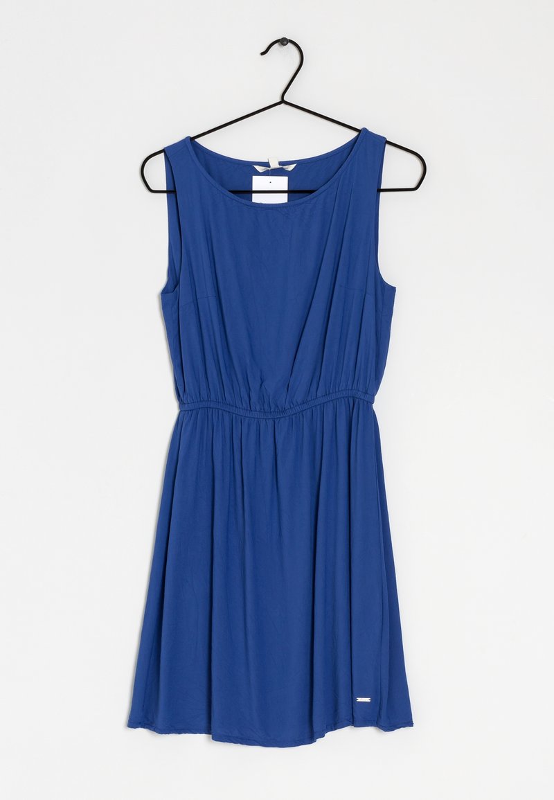 Robe bleue sans manches avec taille froncée suspendue sur un cintre noir sur fond blanc uni.