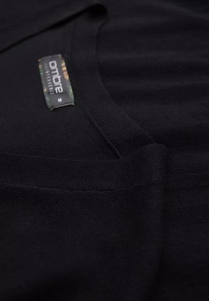 Zwarte gebreide trui met een V-hals ontwerp, geribbelde afwerking en een gemerkt label met groene en gouden accenten op de kraag.