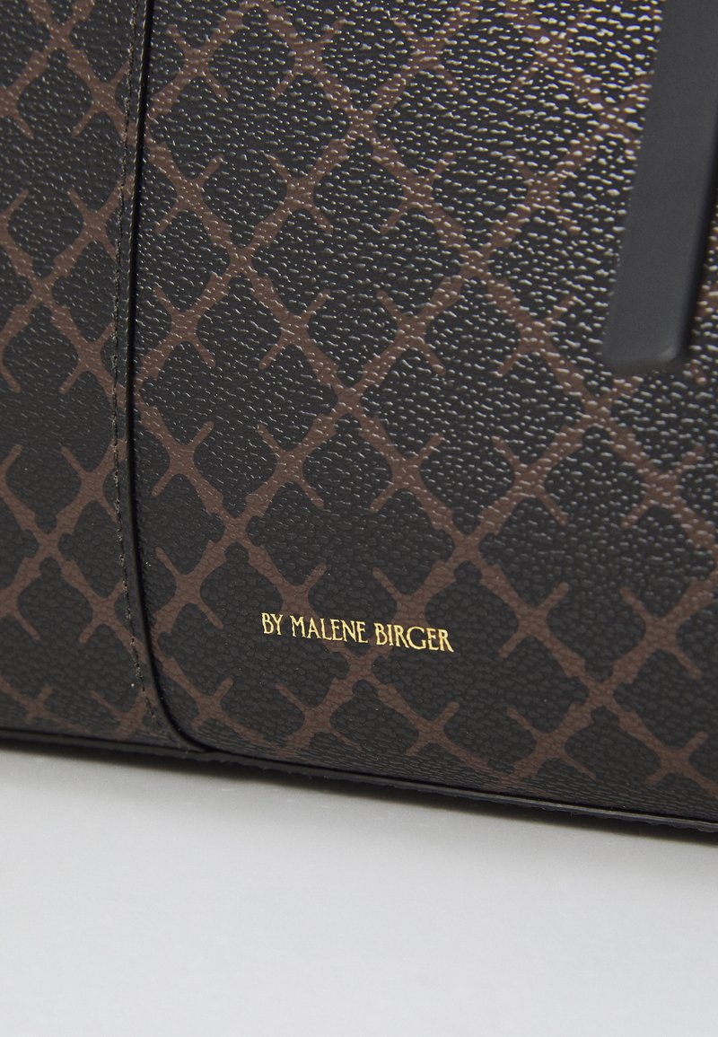 Materiale nero texture con un motivo a rombi marrone. Presenta testo dorato "BY MALENE BIRGER" e un design elegante e minimalista.