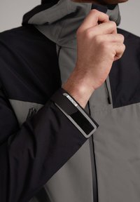 Giacca impermeabile in nero e grigio, con zip e maniche a contrasto con regolazione in Velcro. Tessuto liscio e durevole.