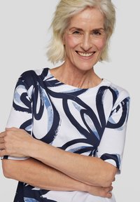 Short-sleeve top in white with a navy blue abstract pattern. Made of soft fabric with a round neckline and relaxed fit.