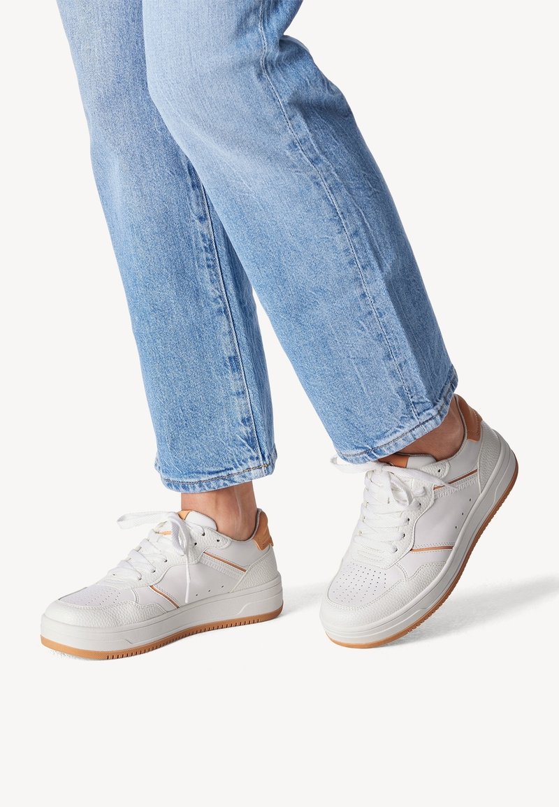 Baskets blanches en cuir avec des accents beiges, bout rond, design perforé sur la boîte à orteils et semelle en caoutchouc texturée.