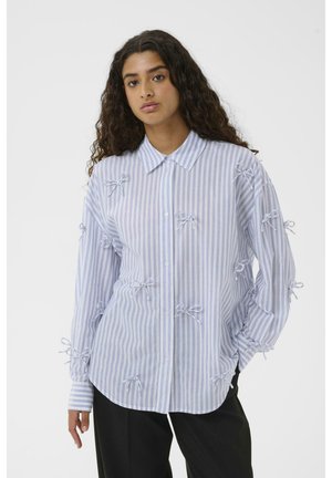 Striped cotton shirt in light blue and white, featuring decorative bow accents and a classic collar. Long sleeves with button cuffs.