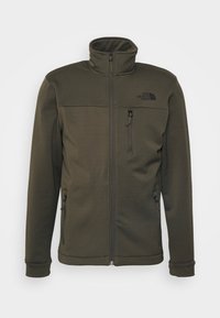 Fleecová bunda olivově zelené barvy s vyšším límcem, zapínáním na zip po celé přední straně a dvěma bočními kapsami. Má také kapsu na zip na hrudi a logo na hrudi.