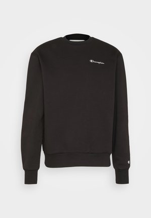 Czarna bluza z dzianiny z okrągłym dekoltem i długimi rękawami, małe białe logo „Champion” na piersi oraz mniejsze logo na mankiecie lewego nadgarstka.