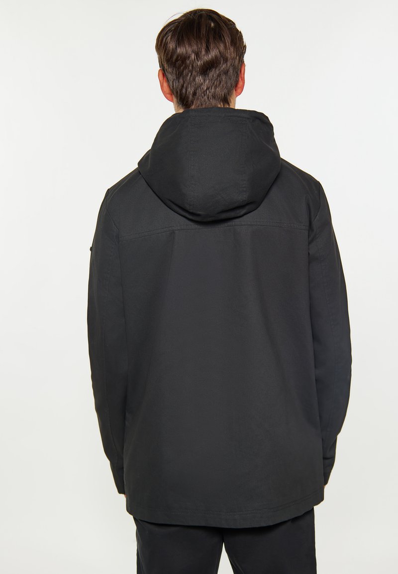 Schwarze Kapuzenjacke mit minimalistischer Gestaltung, ausgestattet mit einer glatten Textur und einem leicht längeren Schnitt, sichtbaren Nähten entlang der Säume.
