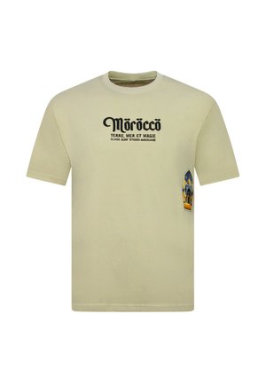 Beige T-shirt met zwarte tekst "Morocco Terre, Mer et Magie" en klein kleurrijk moskeeontwerp aan de rechterkant.