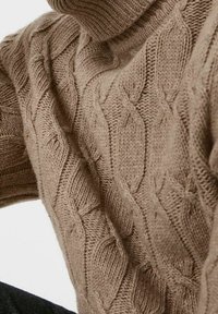 Sweter z dzianiny w kolorze jasnobrązowym, wykonany z wełny, z wysokim kołnierzem i teksturowanym wzorem z przeplatanymi diamentami i liniami.