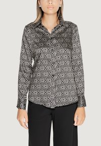 Camicia a maniche lunghe bianca e nera con un motivo geometrico, dotata di colletto e realizzata in un tessuto liscio e lucido.