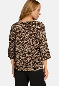 Leopardenmuster-Bluse mit lockerem Schnitt, dreiviertel Ärmeln und weitem Ausschnitt. Hergestellt aus weichem Stoff mit strukturierter Optik.