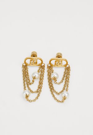 Boucles d'oreilles en ton doré présentant des chaînes superposées avec des perles blanches. Le design comprend un raccord oval qui relie les chaînes et les perles.