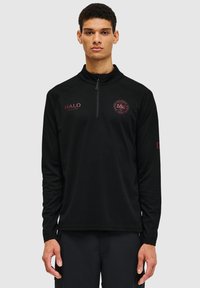 Svart långärmad pullover med en kvartdragkedja, strukturerad tyg, med vinröda logotyper och detaljer framtill och på ärmen.