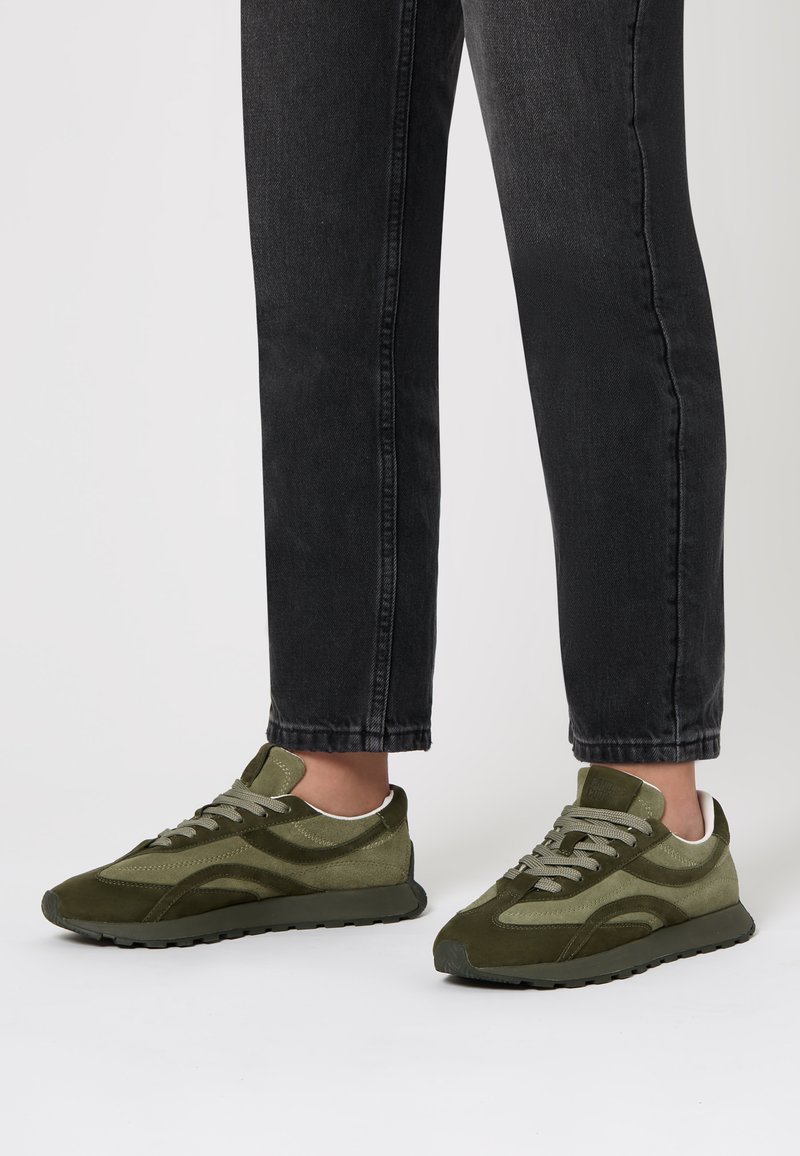 Zapatillas verde oliva de materiales mixtos, con un acabado de ante, acentos texturizados, cordones prominentes y una suela de goma negra.