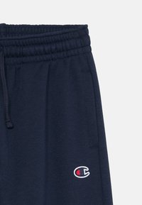 Marine joggers met een elastische tailleband en trekkoord. Voorzien van zijzakken en een klein geborduurd logo op het linkerbeen. Vlotte textuur, katoenmix.
