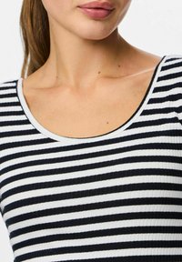 Černobílý pruhovaný top s žebrovanou strukturou a širokým výstřihem, s rovnoměrnými horizontálními pruhy po celé látce.