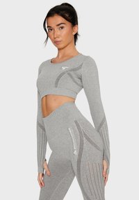 Grey athletic crop top and high-waisted leggings, featuring textured accents and cut-out details. Logo printed on the legging.