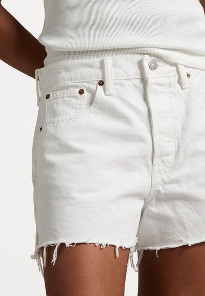 Λευκά τζιν σορτς με φθαρμένο τελείωμα, διαθέτοντας εξαρτήματα σε χάλκινη απόχρωση και σχέδιο πέντε τσεπών. Το υλικό έχει υφή.