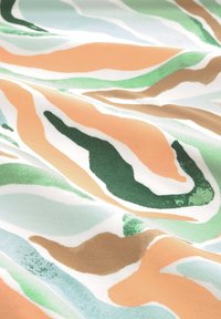 Tissu avec motif ondulé abstrait en vert, pêche, marron et blanc, montrant des plis doux et une texture subtile.