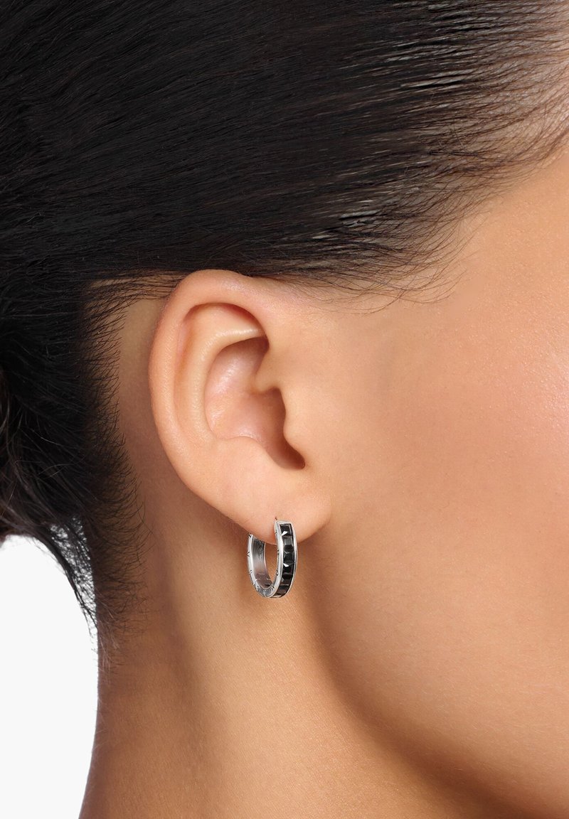 Orecchini a cerchio in argento con un'inserto in smalto nero lucido. Forma arrotondata, superficie liscia, dotati di una chiusura sicura per il fissaggio.
