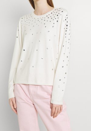 Maglione color crema con paillettes argento sparse sul davanti e sulle maniche. Caratterizzato da un collo rotondo e polsini a costine.