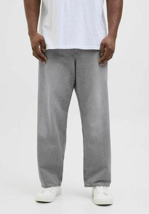 Graue Denim-Hosen mit entspannter Passform, leichtem Fade, Fronttaschen und weißen Turnschuhen. Die lockere Silhouette erhöht den Tragekomfort.