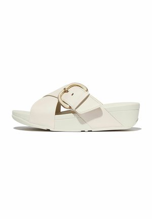 Sandale compensée beige à bout ouvert avec une large sangle traversant le pied et une grande boucle métallique sur le côté.