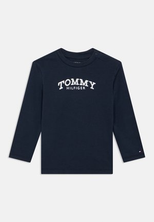 Marineblaues Langarmshirt für Kleinkinder mit "TOMMY HILFIGER" in Weiß auf der Brust gedruckt und kleinem Markenflaggen-Emblem am Ärmelabschluss.