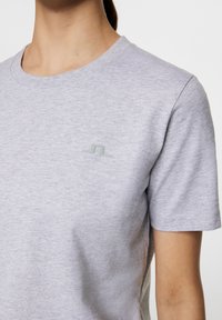 Szara krótko rękawowa koszulka z miękkiej dzianiny bawełnianej, z okrągłym dekoltem i małym wytłoczonym logo na piersi.