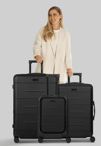 Set di bagagli neri composto da tre dimensioni: grande, media e da cabina. Realizzato in materiale resistente con texture lisce e maniglie retrattili.