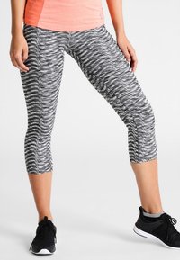 Černo-bílé legíny capri s vzorem, vyrobené z pružného, lehkého materiálu, s plochým pasem a délkou do poloviny lýtek.