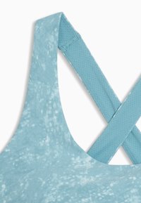 Λουράκι αθλητικού σουτιέν σε ανοιχτό μπλε με διασταυρούμενο σχεδιασμό, υφή και λεία επιφάνεια. Διαθέτει διαπνέον πλέγμα.