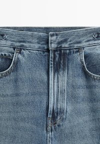 Hellblaue Jeans mit hohem Bund, fünf Taschen und einem ausgewaschenen Effekt. Nähdetails in kontrastierendem Garn um den Bund.