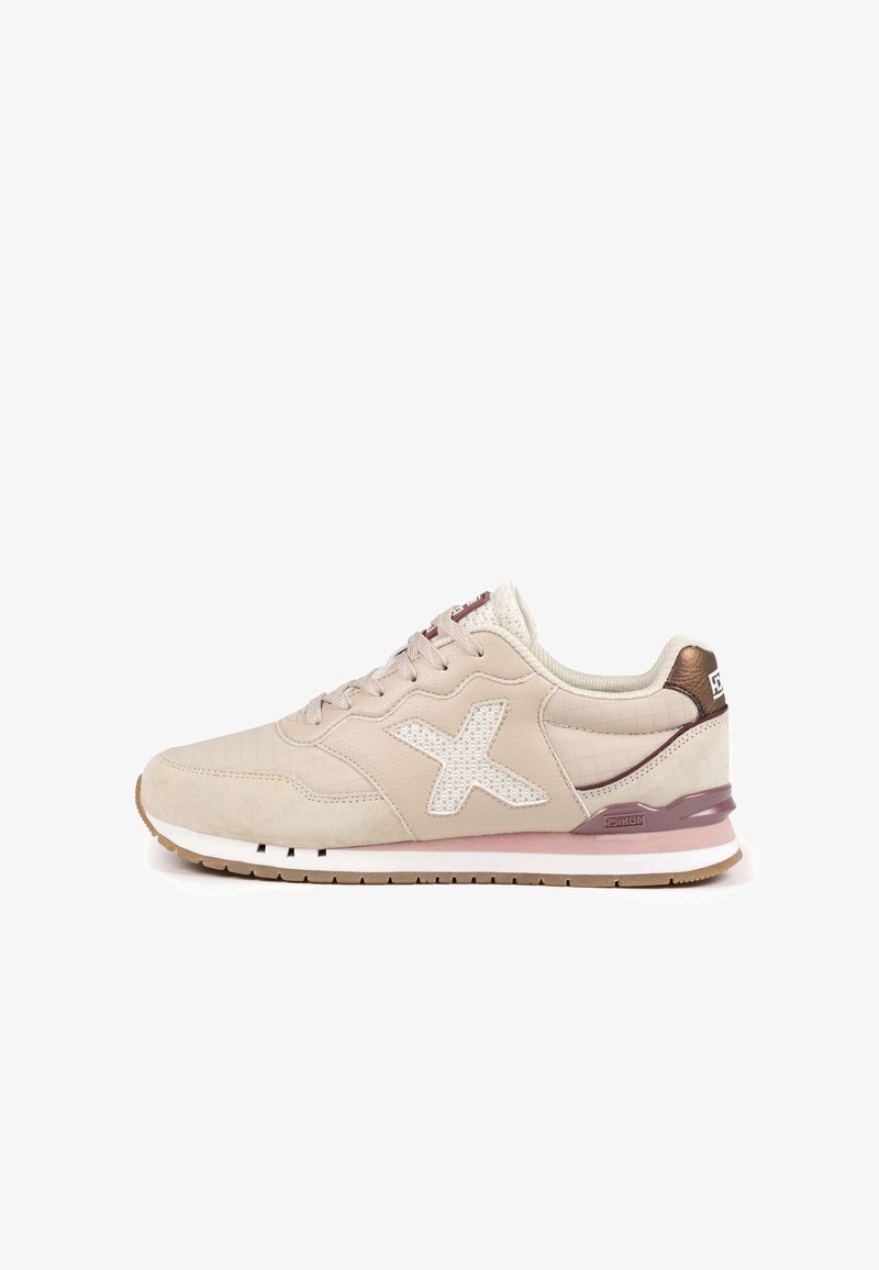 Chaussure de sport beige présentant une texture matelassée, un motif étoile en mesh blanc, et des accents bruns sur le talon. Semelle en caoutchouc avec une semelle intermédiaire rose clair.