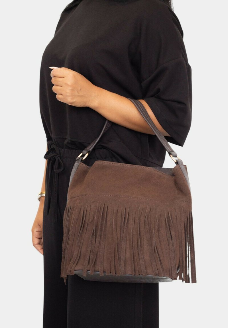 Bolso de ante marrón con detalles de flecos, una superficie texturizada y una única correa para el hombro. El bolso tiene un diseño estructurado con forma redondeada.