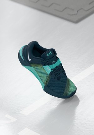 Sportsko med en marineblå overdelf, lyseblå og grønne accenter, struktureret mesh-materiale, rund tå og fleksibel gummisål.
