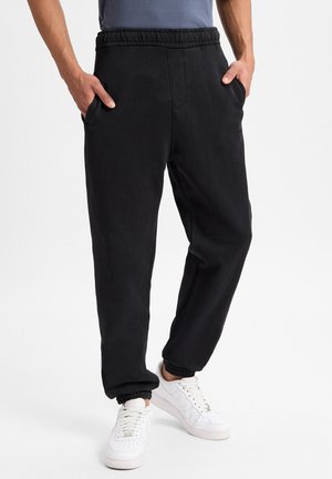  Sorte joggerbukser med elastisk talje, sidelommer og tætsiddende cuffs. Fremstillet af blødt stof, med en glat tekstur og simpelt design.