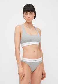 Sivý rebrovaný bralet a zodpovedajúce bikiny, s bielymi elastickými pásikmi s logom. Mäkká tkanina, bezšvový dizajn, priliehavý strih.